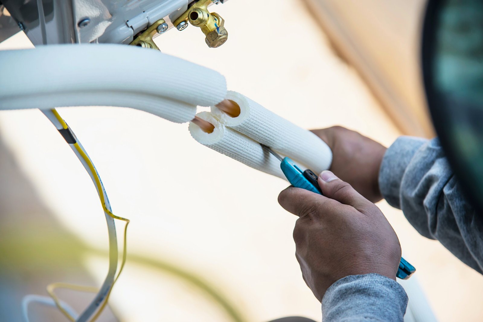 Man is installing wall compressor of air conditioner during hot season